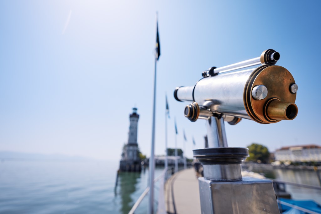 Fernglas ist auf den Bodensee gerichtet und zeigt den Hafen von Lindau.